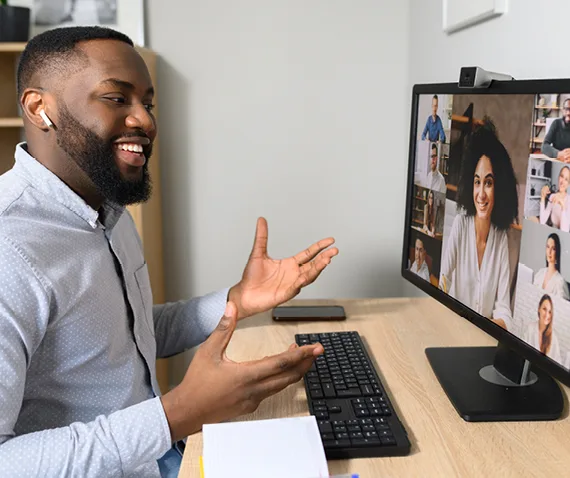 Man at his desk speaking to people in a virtual meeting